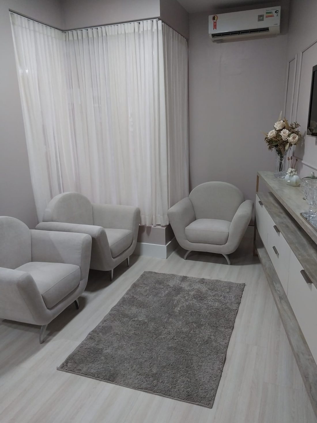 Sala de atendimento com duas poltronas claras e tapete